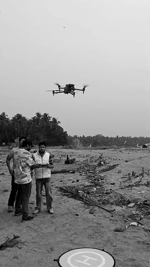 A drone hovering above engineers on a beach.